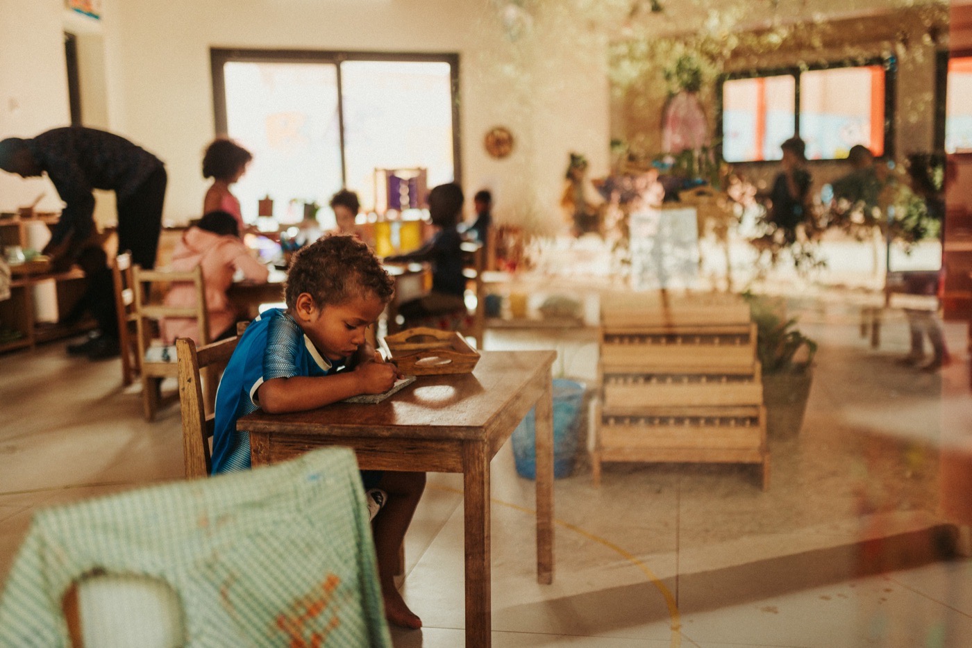 Enfant à table en cantine, soleil traversant la pièce