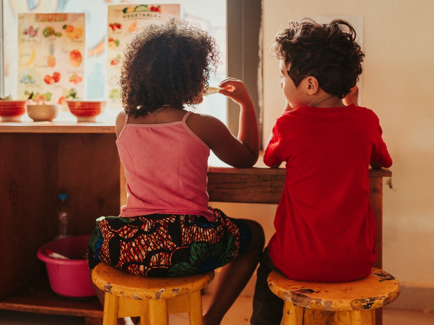 Deux enfants devant les affiches de fruits et légumes